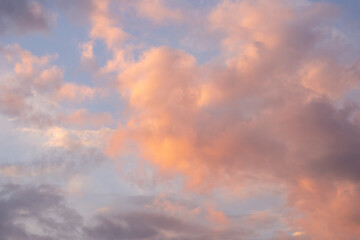 Pink fluffy clouds on blue sky, sunset. Beautiful evening landscape.