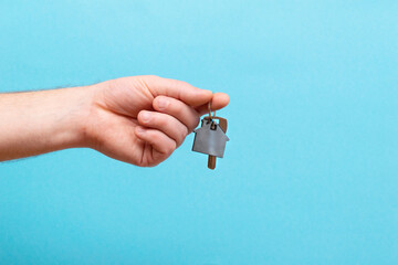 The hand holds the keys with the house keychain. Purchase of apartments.