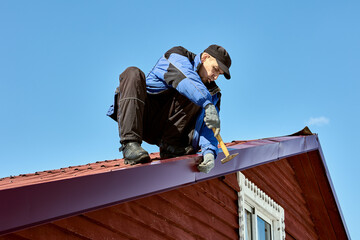 Restoring roof after hurricane, roofer fixes tin sheets torn off by wind on roof.