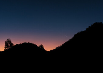 Sunset colours, mountain silhouette and crescent moon rise, over the Blue Mountains in New South Wales, Australia