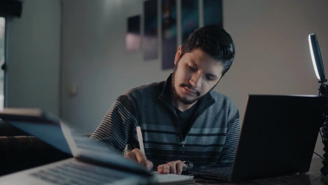 Young man taking notes from his virtual class