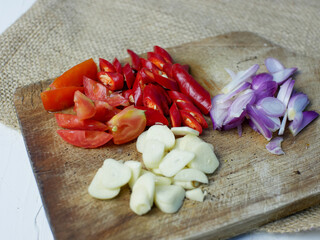 sliced onions, garlic, and red chilies on a wooden cutting board. kitchen spice concept