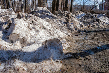 Dirty snow bank. Frozen snowdrift mixed with earth. Winter day. Environmental pollution. Cleaning, clearing streets from snow