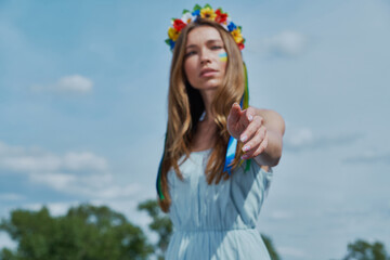 Beautiful young Ukrainian woman stretching out hand with blue sky in the background