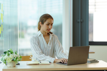 Portrait of young Asian business woman using laptop computer in the office.