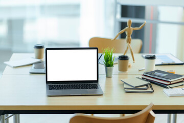 Laptop computer with blank white screen on table in the office. mock up.