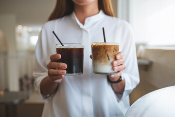 Closeup of a woman holding and serving two glasses of iced coffee