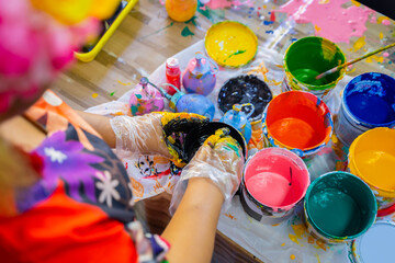 An art teacher is preparing different colors for the children. Kindergarten teacher and acrylic paint for kids - obrazy, fototapety, plakaty