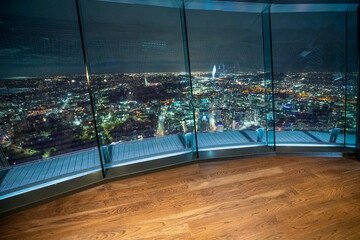Night aerial city view from the top of a high tower. City lights through the glasses