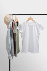 Blank white female t-shirt mockup. Basic women`s clothes. Woman collection of clothes on a rack. Spring and summer fashion trending concept. Railing with stylish female clothes