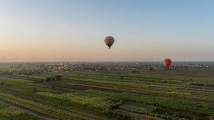 Balloons fly over agricultural plantations. Green fields below. The morning sky is highlighted...