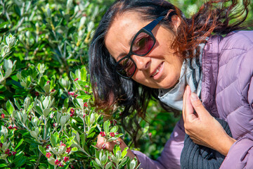 A woman sniffs flowers in a park