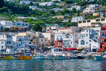 Fototapeta na wymiar Capri, Italy - June 18, 2021: Tourists and restaurants in the small port of Capri