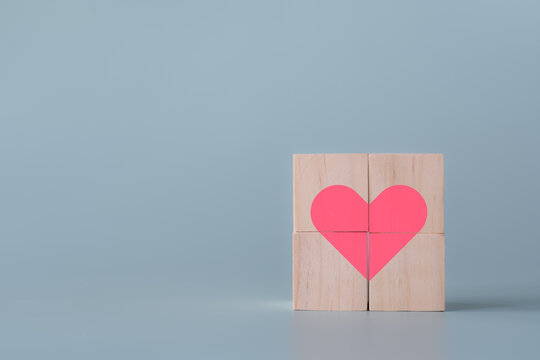 Pink heart in cube wooden blocks light blue background healthcare and emotional concept. Heart shape shows care and love in square wooden toy blocks.