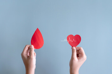 Blood donation or medical surgery concept. Human holding small piece of paper blood sign and a red...