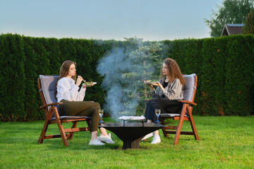 Two women having late evening barbecue picnic