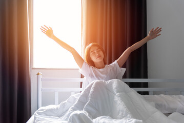 woman stretching her arms in bed after waking up