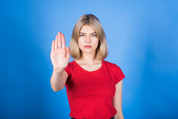 Young caucasian blonde girl in casual clothes showing stop gesture with hand and palm, reject sign,...