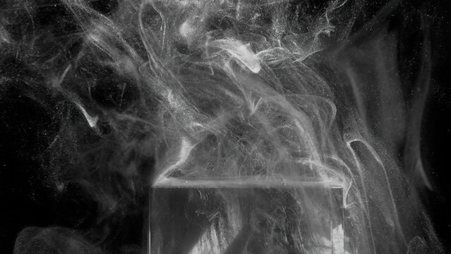 Glitter smoke splash. Mist haze. Grain fume texture. Silver vapor floating over glowing ice cube edge on dark black mystical abstract background.