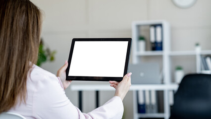 Computer mockup. Online connection. Office work. Unrecognizable woman holding tablet computer with blank screen in light office room interior copy space.