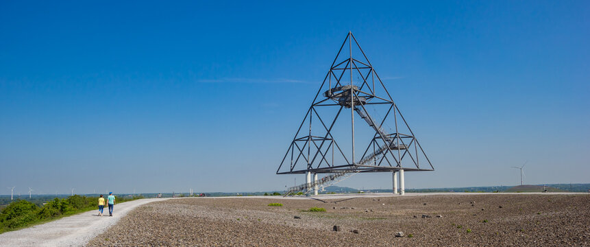 Panorama of a young couple walking to the tetrahedron in Bottrop, Germany
