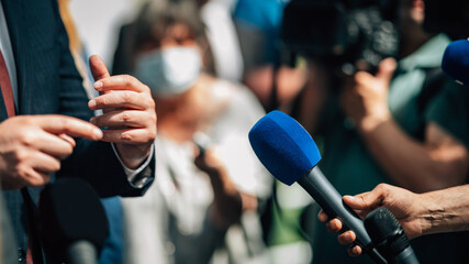Media interview, a politician answering questions at a media press conference, reporter holding a microphone. - obrazy, fototapety, plakaty