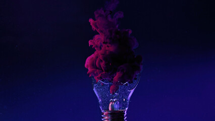 Ink water shot. Light bulb explosion. Fantasy splash. Neon magenta pink smoke cloud in broken lamp glass on navy blue color gradient abstract art copy space background.