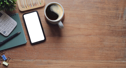 Mock up smart phone, coffee cup and notebook on wood table. Top view.
