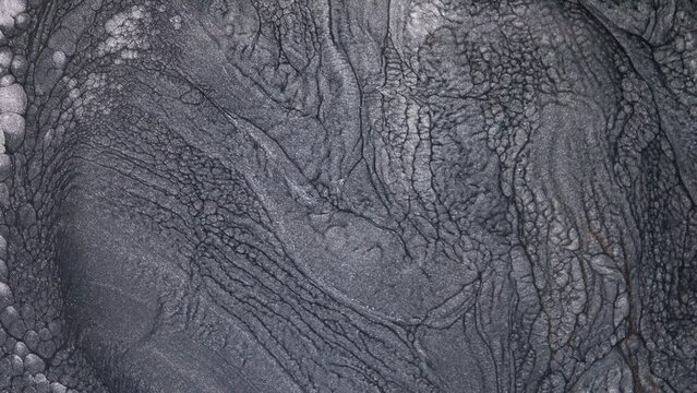 Abstract fluid background design of moving monochrome liquid silver shimmering ink. Lava flow, melting and seething of metals