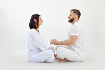 Man and woman, couple in love, wear white outfit, practice Pilates and yoga, sit in lotus pose. Conscious tantra love - obrazy, fototapety, plakaty