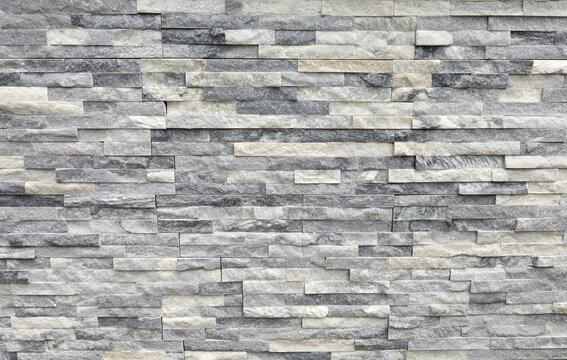 Fototapeta Stone cladding wall made of regular  bricks of white, gray and black rocks. Panels for exterior, background and texture. 