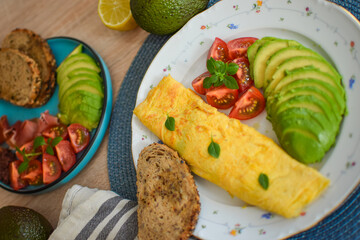 French omelet filled with cheese. Plating with avocado and cherry tomatoes.