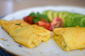 French omelet filled with cheese. Plating with avocado and cherry tomatoes.