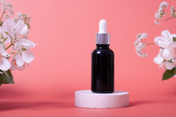 Cosmetic glass dropper bottle with oil, serum or fruit peeling on podium with jasmine flowers. Beauty product presentation on natural background. Front view. Mockup concept