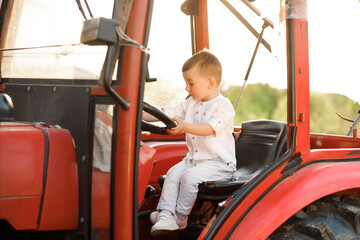 Little boy sitting in a tractor at sunset