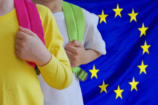 Two children with satchels background of EU flag. Concept of upbringing and educating children in European Union