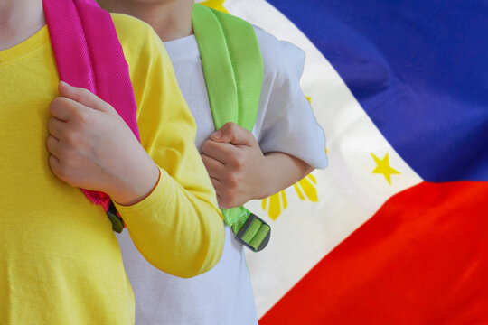 Two children with satchels background of Philippines flag. Concept of upbringing and educating children in Philippines