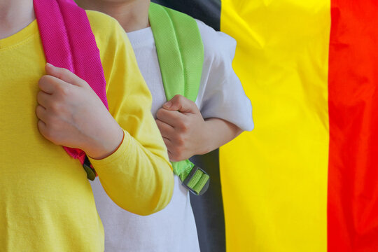 Two Children With Satchels Background Of Belgium Flag. Concept Of Upbringing And Educating Children In Belgium