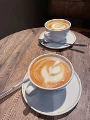Coffee hearts - cappuccino in white coffee cups on wooden table - 510527933
