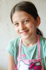 cute little girl in a kitchen apron and with flour on her cheek