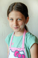 cute little girl in a kitchen apron and with flour on her cheek