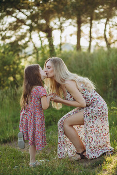 Happy family on a summer meadow. little girl child daughter hugging and kissing mother