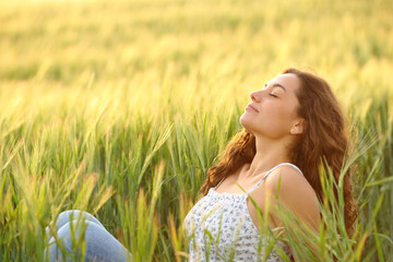 Woman relaxing breathing sitting in a field at sunset
