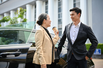 Successful Aged asian businesswoman and professional businessman standing in front the car.