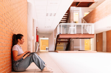 Focused woman browsing laptop near brick wall