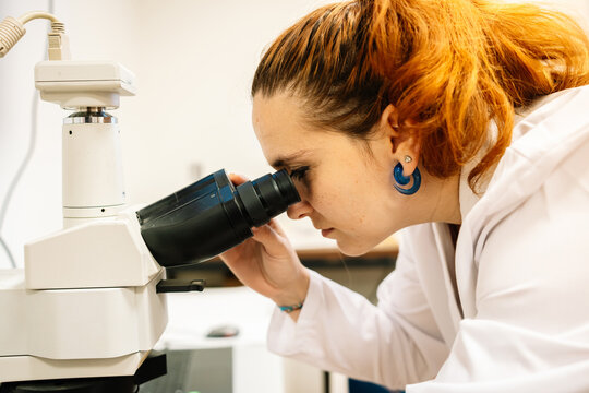 Focused scientist looking through microscope in lab
