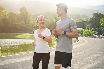 Two asian sporty aged woman and millennial male running or jogging together.