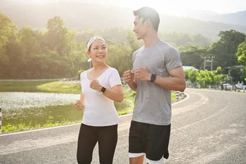 Deurstickers Two asian sporty aged woman and millennial male running or jogging together. © bongkarn
