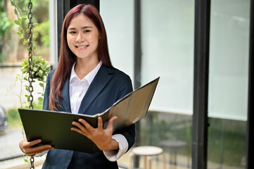 Obraz premium Portrait of a beautiful young asian businesswoman in formal suit with a document folder