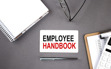 EMPLOYEE HANDBOOK Text written on the card with notebook and clipboard, grey background - obrazy, fototapety, plakaty